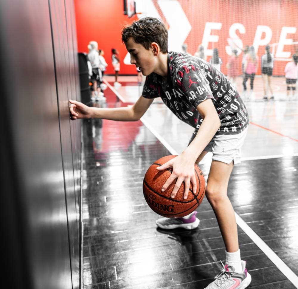 young athlete dribbling basketball touching a wall