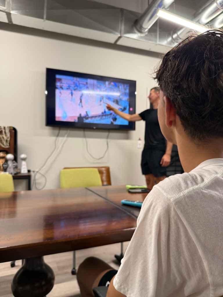 coach ro points at a tv during a film review session